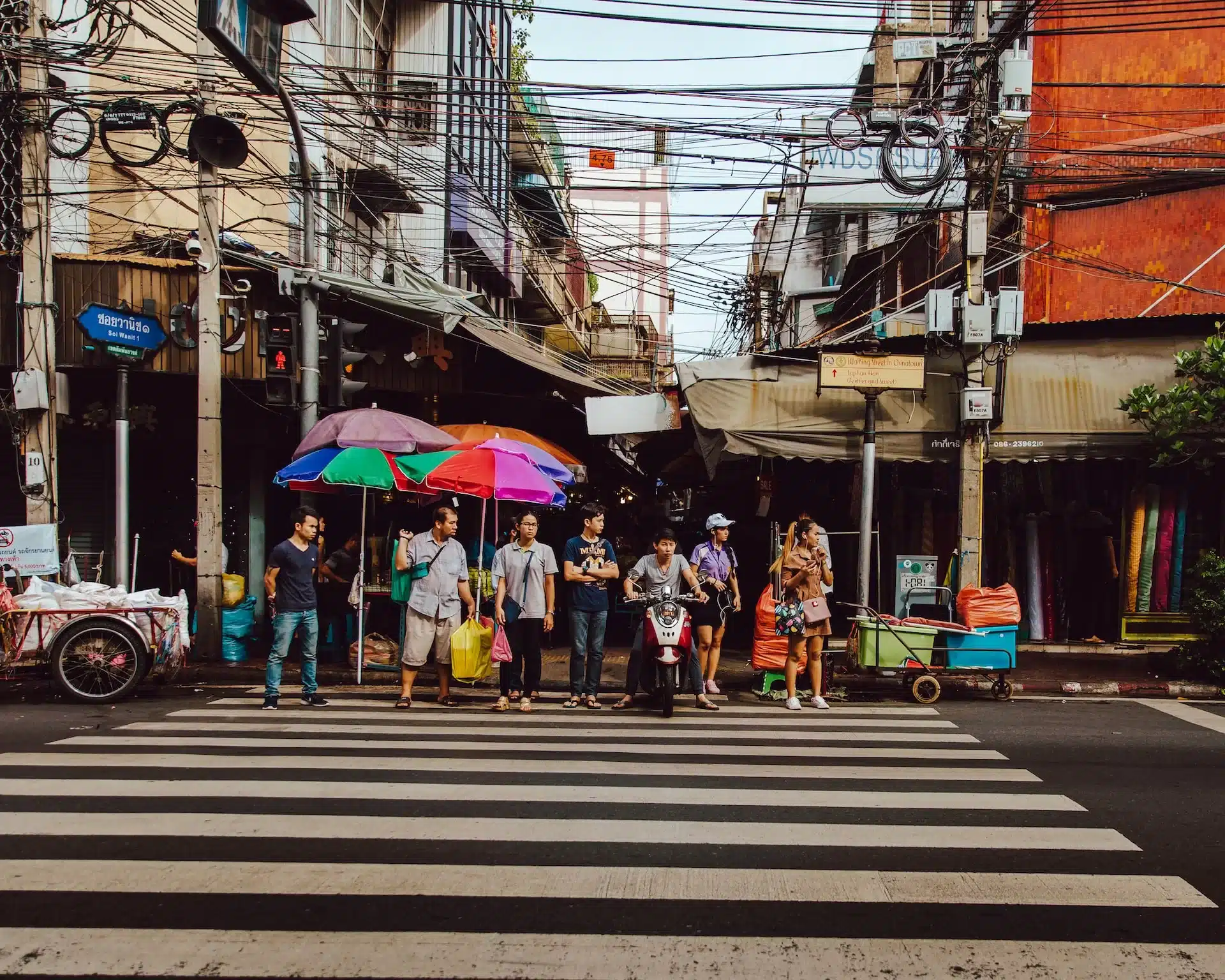 People crossing a street in Bangkok's old town.